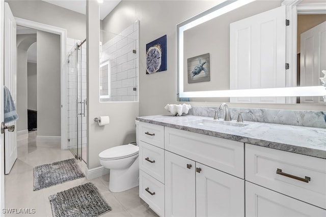 bathroom featuring vanity, a shower with door, toilet, and tile patterned floors