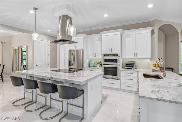 kitchen featuring appliances with stainless steel finishes, white cabinets, island range hood, pendant lighting, and sink