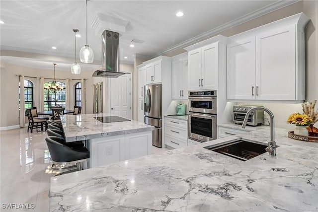 kitchen with appliances with stainless steel finishes, island range hood, pendant lighting, and white cabinetry