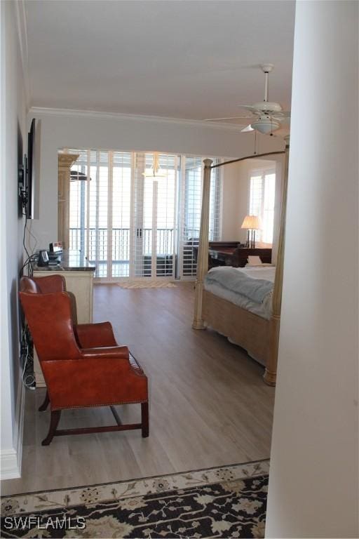 bedroom with multiple windows, a ceiling fan, crown molding, and wood finished floors