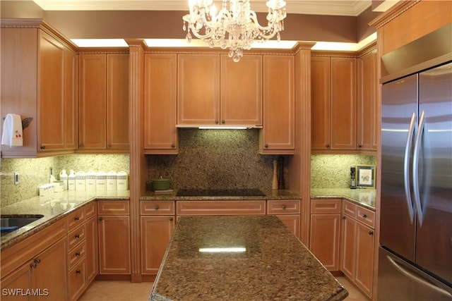 kitchen with pendant lighting, dark stone countertops, and built in fridge