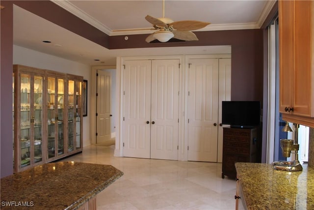 interior space with ornamental molding, ceiling fan, and two closets