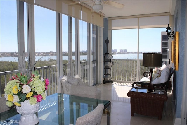 sunroom / solarium featuring a water view and a ceiling fan