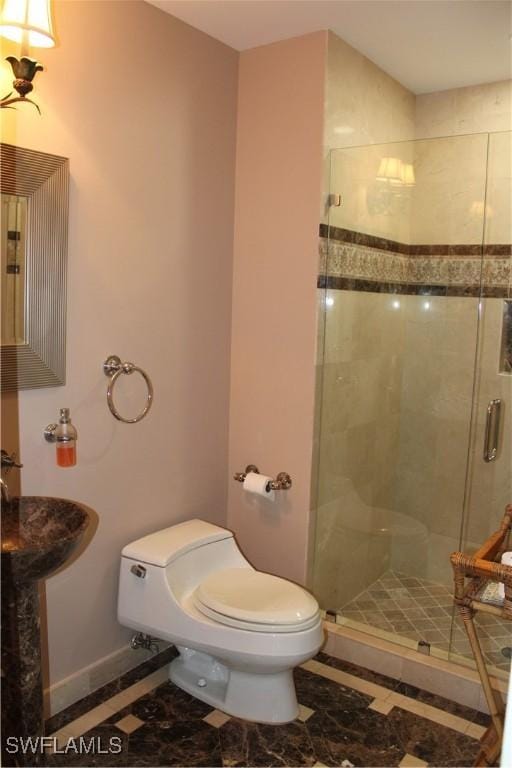 bathroom featuring a shower stall, toilet, and baseboards