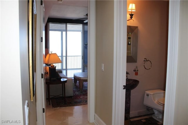 bathroom with baseboards, a healthy amount of sunlight, ceiling fan, and toilet