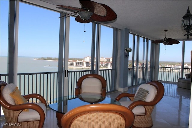 sunroom featuring a water view and a ceiling fan