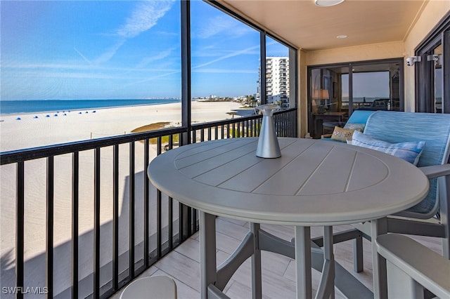 sunroom / solarium featuring a beach view and a water view