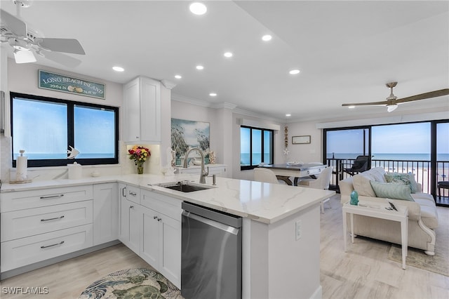 kitchen featuring a peninsula, a water view, a sink, white cabinets, and stainless steel dishwasher