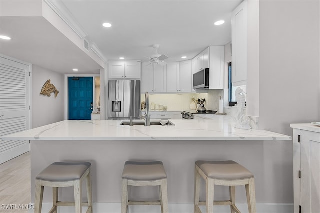 kitchen with stainless steel appliances, a breakfast bar, a sink, and a peninsula