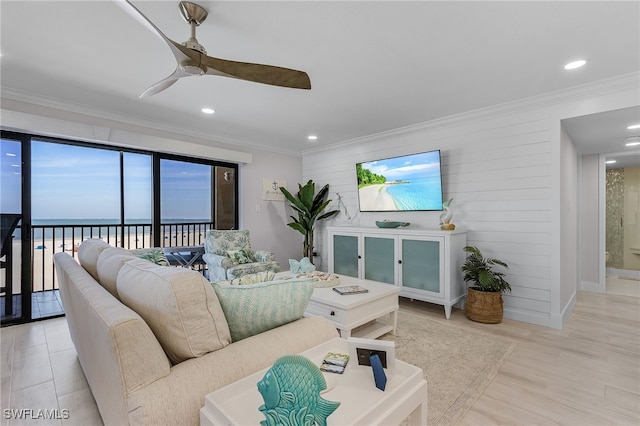 living room featuring light wood finished floors, a ceiling fan, ornamental molding, a water view, and recessed lighting