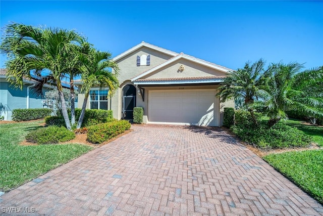 view of front of house featuring decorative driveway, an attached garage, and stucco siding