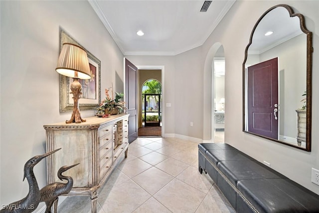 entrance foyer featuring light tile patterned floors, baseboards, visible vents, arched walkways, and ornamental molding