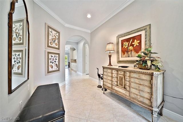 hallway featuring arched walkways, ornamental molding, light tile patterned flooring, and baseboards