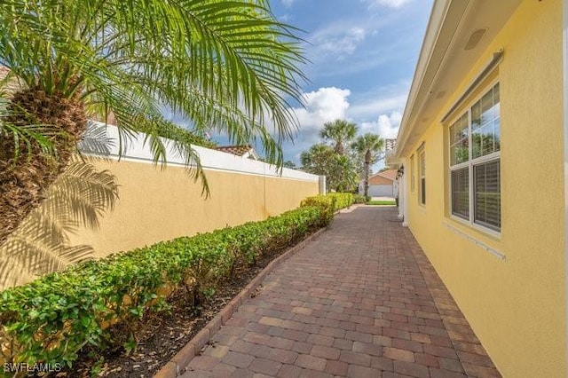 view of side of home with fence and stucco siding