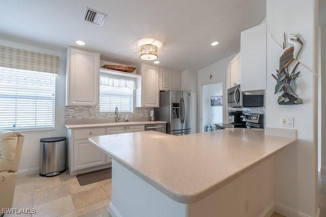 kitchen featuring a peninsula, white cabinetry, visible vents, and appliances with stainless steel finishes