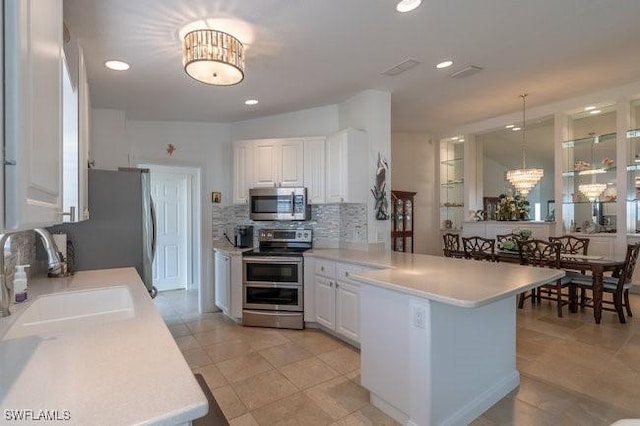 kitchen with a peninsula, appliances with stainless steel finishes, light countertops, and white cabinetry