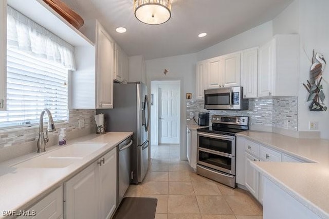 kitchen featuring appliances with stainless steel finishes, light countertops, white cabinets, and a sink