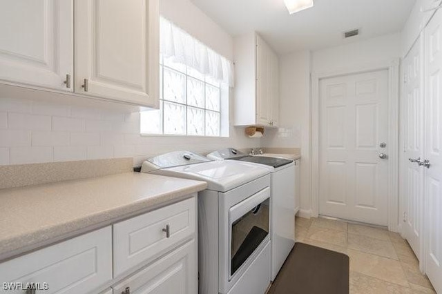 clothes washing area with cabinet space, visible vents, washing machine and clothes dryer, and light tile patterned floors