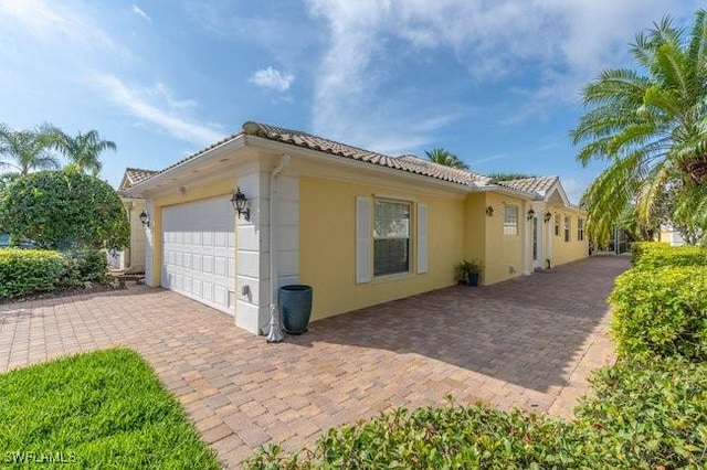 view of home's exterior featuring a garage, a tile roof, and stucco siding