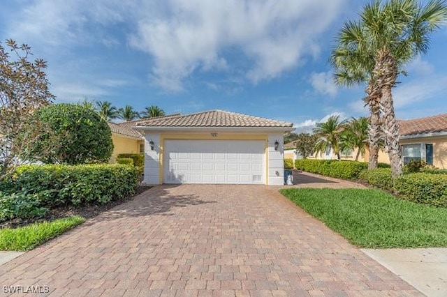 view of front of property featuring a garage, a tiled roof, decorative driveway, and stucco siding