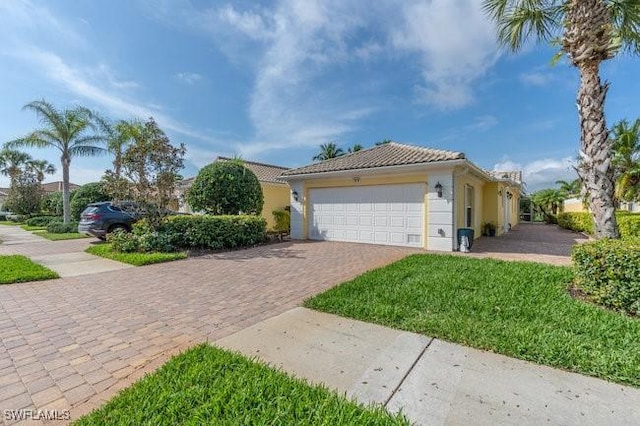 view of front of house with an attached garage, a tile roof, decorative driveway, and stucco siding