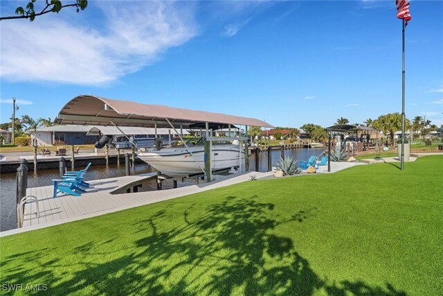 dock area with a water view, boat lift, and a yard