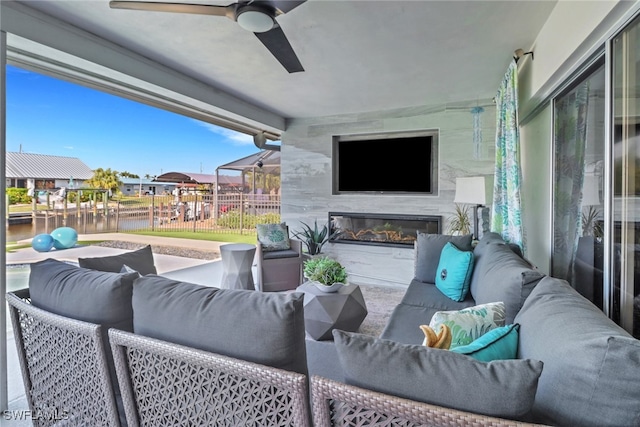 view of patio / terrace with a ceiling fan, a water view, fence, and an outdoor living space with a fireplace