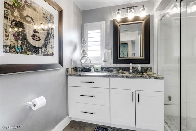 bathroom featuring a shower with door, baseboards, and vanity