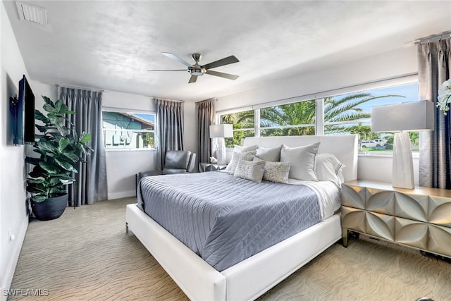 bedroom with light carpet, baseboards, visible vents, and a ceiling fan