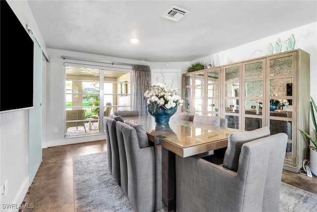 dining area featuring visible vents, concrete floors, and baseboards