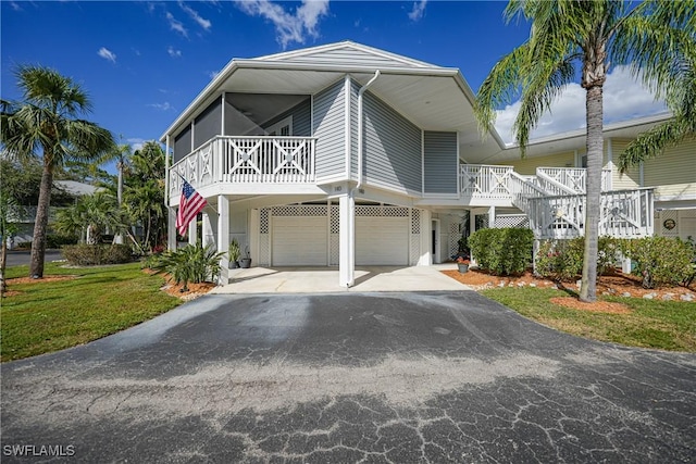 raised beach house featuring a garage and a front lawn