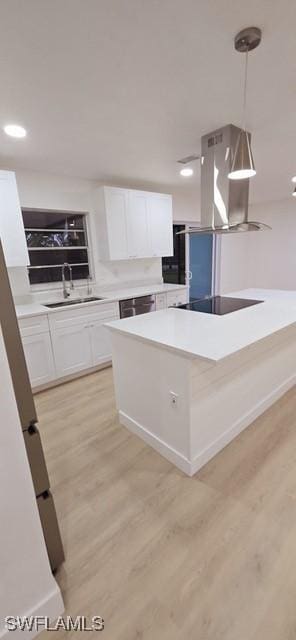 kitchen featuring sink, light hardwood / wood-style flooring, white cabinetry, and pendant lighting