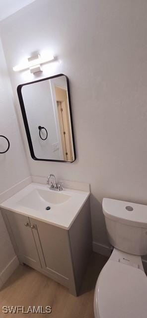 bathroom with hardwood / wood-style flooring, vanity, and toilet