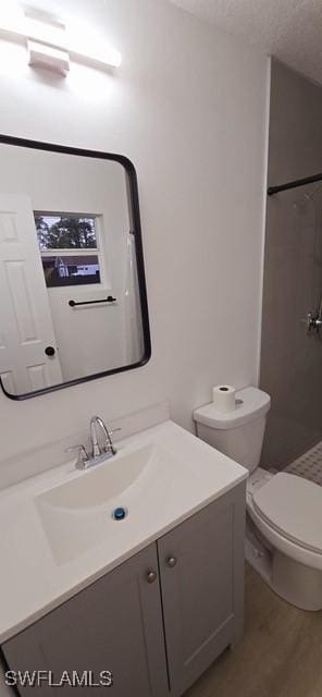 bathroom featuring a shower, toilet, wood-type flooring, a textured ceiling, and vanity