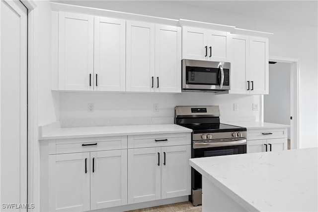 kitchen with white cabinets, stainless steel appliances, and light stone counters