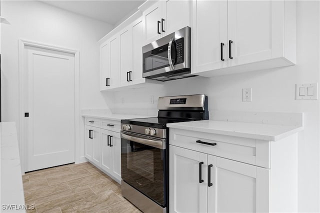 kitchen with appliances with stainless steel finishes, white cabinetry, and light stone countertops