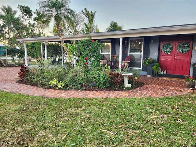 entrance to property with covered porch and a lawn