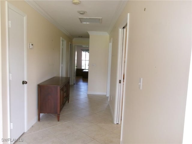 hall featuring baseboards, ornamental molding, and light tile patterned flooring