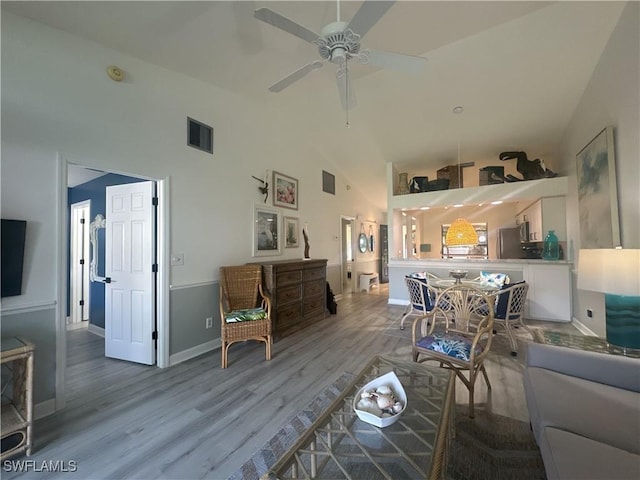 living area with baseboards, visible vents, ceiling fan, wood finished floors, and high vaulted ceiling