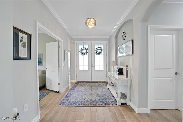 foyer with light wood-type flooring, ornamental molding, arched walkways, and french doors