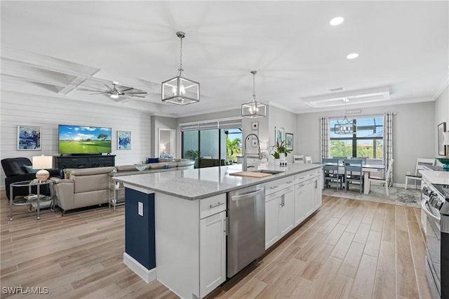 kitchen with appliances with stainless steel finishes, white cabinets, a sink, and light wood finished floors