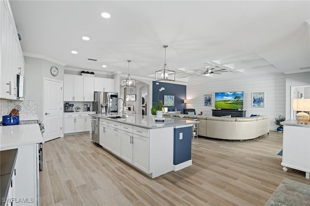 kitchen with decorative backsplash, appliances with stainless steel finishes, light countertops, light wood-style floors, and white cabinetry