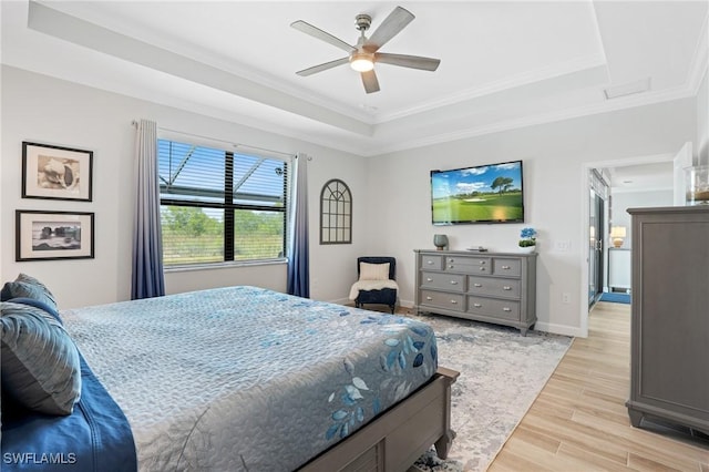 bedroom featuring crown molding, a raised ceiling, light wood-style floors, a ceiling fan, and baseboards