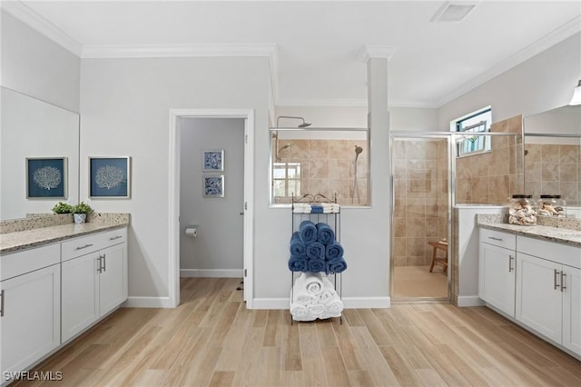 bathroom featuring ornamental molding, a shower stall, and wood finished floors