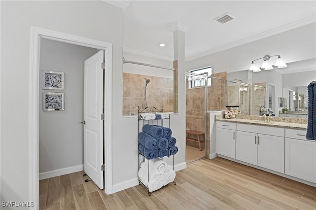 full bath featuring a stall shower, baseboards, ornamental molding, wood finished floors, and vanity