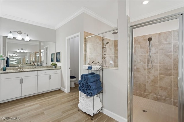 bathroom with wood finished floors, ornamental molding, a shower stall, and toilet