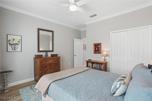 bedroom with baseboards, visible vents, ornamental molding, wood finished floors, and a closet