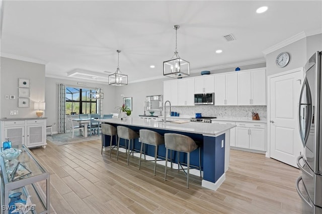 kitchen with tasteful backsplash, white cabinets, stainless steel appliances, light countertops, and light wood-style floors