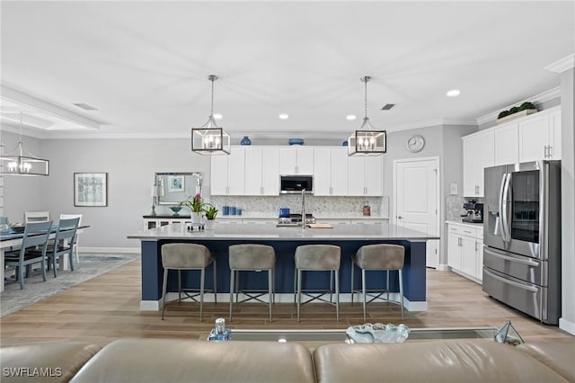 kitchen with appliances with stainless steel finishes, ornamental molding, a kitchen bar, and an inviting chandelier