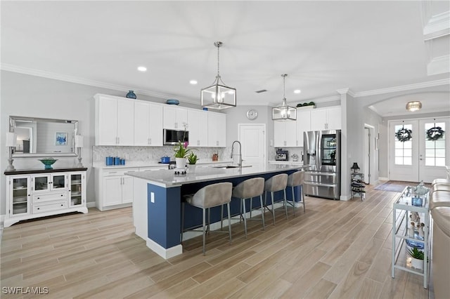 kitchen featuring white cabinets, appliances with stainless steel finishes, a kitchen breakfast bar, wood finish floors, and a sink